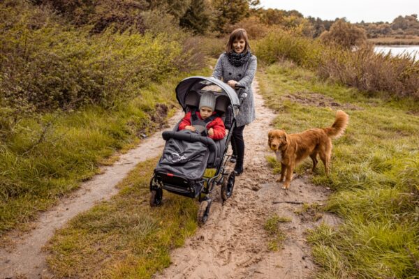 Szczęśliwa mama z dzieckiem w wózku rehabilitacyjnym Comfort oraz psem na spacerze